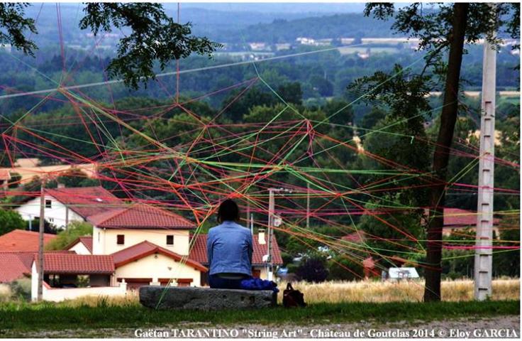 Personne assise devant une œuvre de ficelles